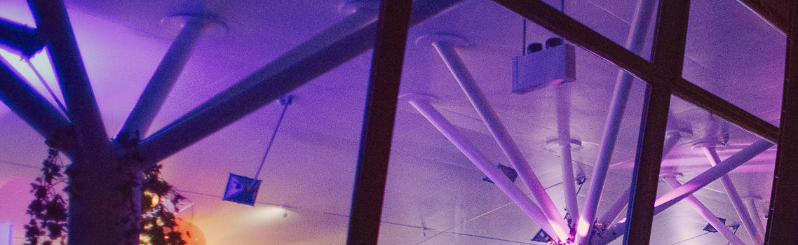 Exterior shot of Ecology Pavilion at night with busy and brightly lit event indoors