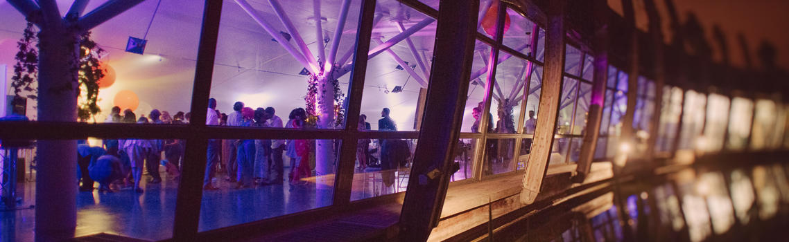 Exterior shot of Ecology Pavilion at night with busy and brightly lit event indoors