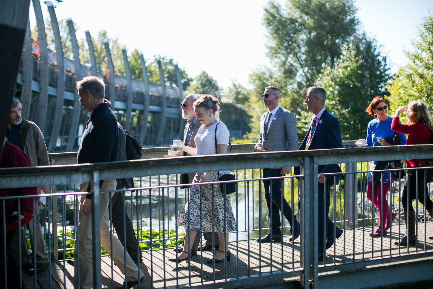 People walking across bridge behind pavilion